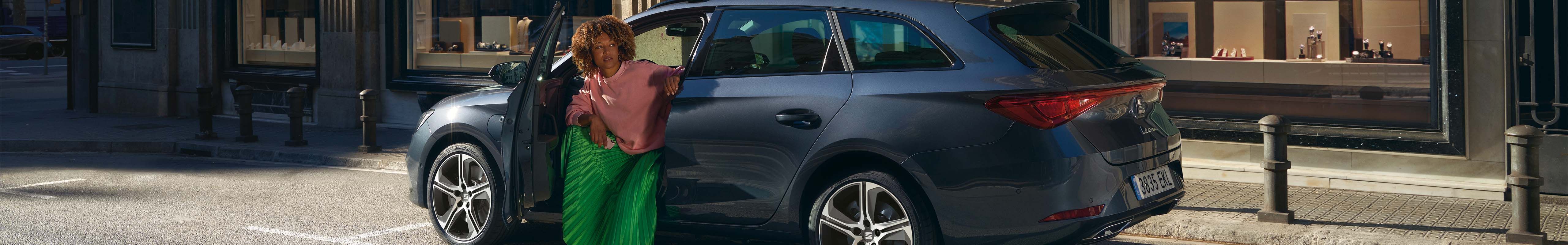 SEAT leon sportstourer hybride en bleu sur la route, conducteur ouvrant la porte de la voiture en ville, ombres